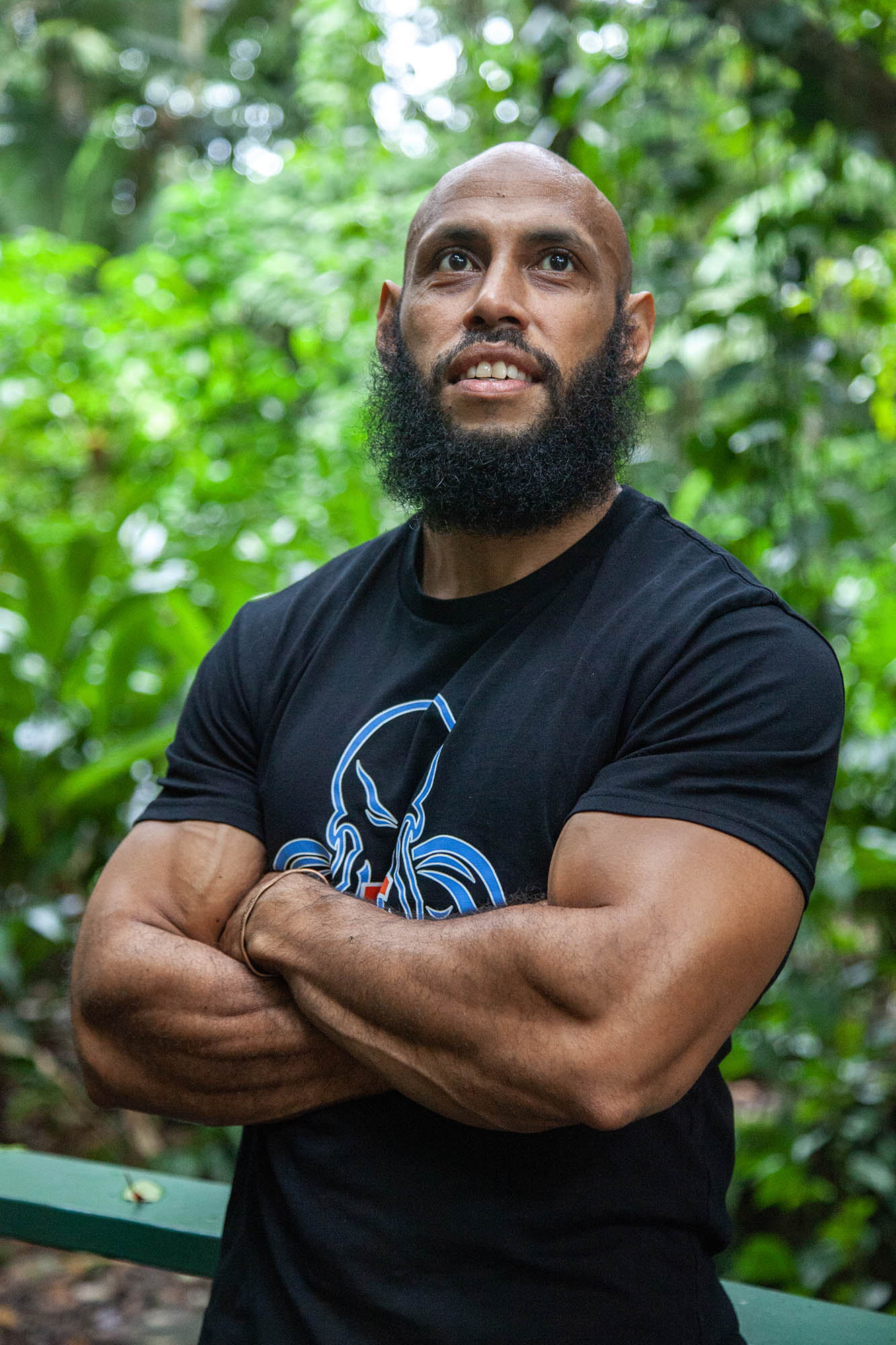 Mengui with arms crossed by tree in Botanical Gardens, Cairns